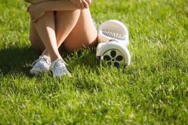 Elektrikli mini vurgulu kurulu scooter üzerinde çim yeşil park kadın var. Eko şehir ulaşım pille, üretmek için atmosfer hava kirliliği