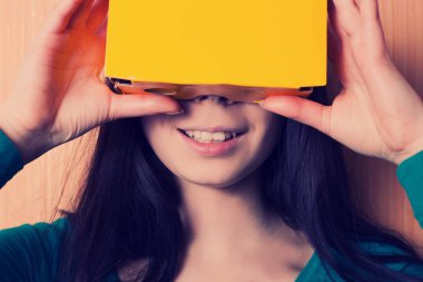 Genç kız onun akıllı karton sanal gerçeklik kulaklık ile video oyunu oynar. Çift hipster film sesi ile yenilikçi teknoloji