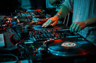 Party dj scratches vinyl record with music on turn table record player in nightclub.Professional club disc jockey scratches records & plays musical set on stage.Concert analog audio equipment for djs clipart