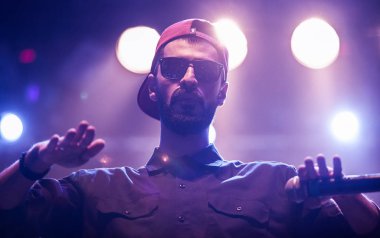 Moskova - 20 Ekim, 2016: Rap şarkıcı şarkı sahne gece kulübü. Hip hop müzik sanatçı şarkı mikrofon sahnede. Rapçi parlak konser aydınlatma.