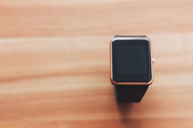 Ahşap arka plan üzerinde döşeme akıllı kol saati. Her zaman sağlar zarif yeni teknoloji bağlı kal. Solma film renkleri