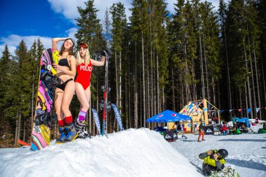 Bukovel, Ukrayna-19 Mart, 2018: Yüzmek iki çekici genç kız giymek snowboard ve Kayak ile poz dağ Park. Kayak yolda poz mutlu turist kadın