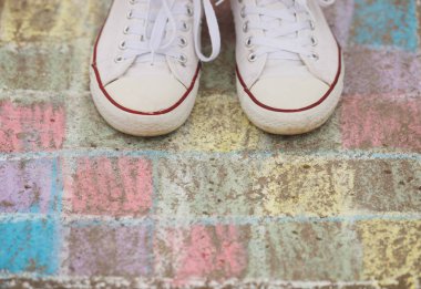 Boya kalemi beton floow açık havada üzerinde çizim üzerinde duran beyaz spor ayakkabı giyen bir çocuk. Trendy sakız ayakkabı, gençlik moda sembolü. 