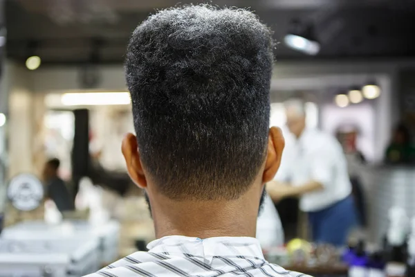 Young black man in barbershop,back view.Unshaven nape and neck of african male model in barber shop salon.Male beauty treatment process