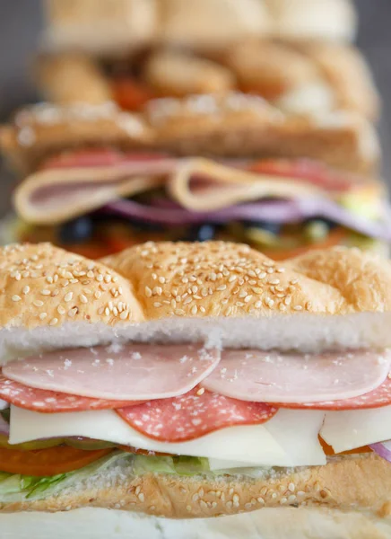 Tasty fresh sandwich in fast food restaurant menu.Delicious snack for lunch.Sliced ham & sausage,cut vegetables,sauce.Natural fastfood dish in cafe menu.Vertical food background