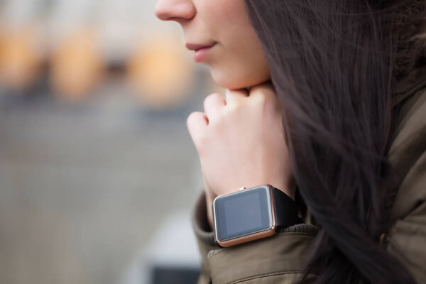 Портрет молодой девушки с модными умными часами на руке. Этот новый гаджет позволяет ей оставаться легко подключен к ее друзьям из социальных сетей через Интернет в ее смартфон
