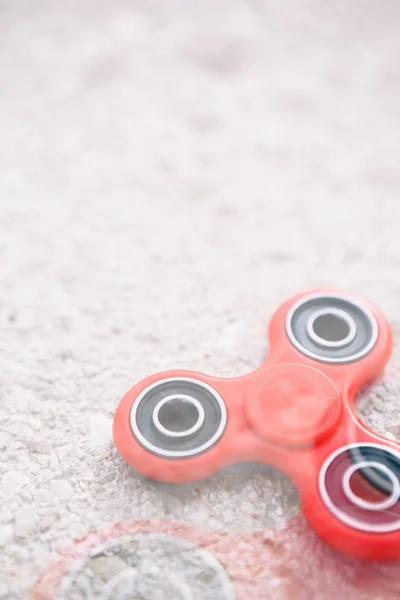 Super popular finger spinner fidget device.Modern red plastic spinning toy with bearings.Play with spinners to improve reaction & learn new cool tricks.Trendy new spinner gadget close up