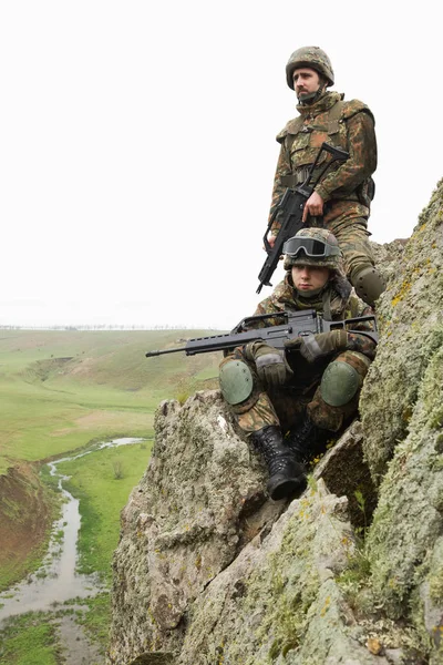 Military assistance.Army teamwork.Armed soldiers in camouflage of Ukrainian army in combat uniform.Soldier helps team member climb rock outdoor.War in Eastern Ukraine.Heavy ammunition,automatic rifle