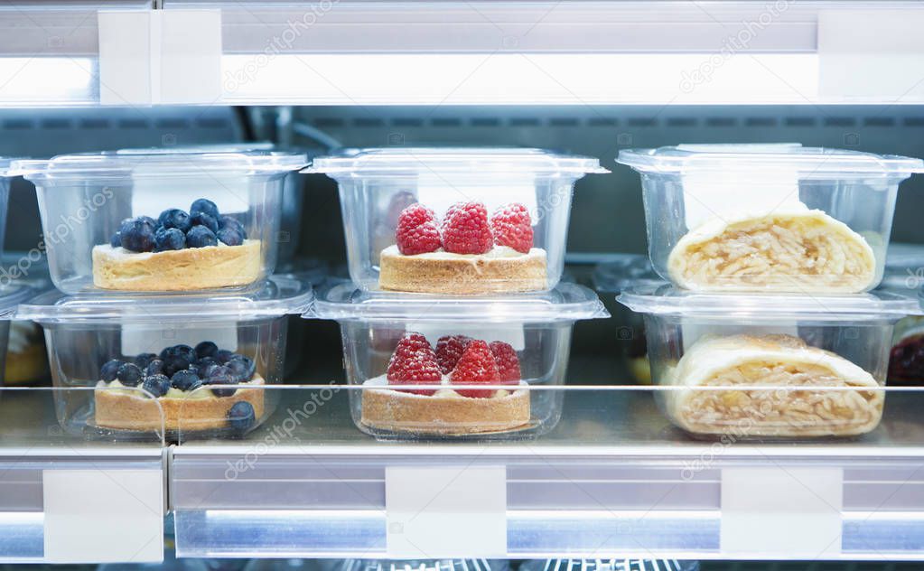 Delicious desserts with berries stored in plastic containers.Food store sell bakery products from refridgerator.Enjoy sweet food for lunch