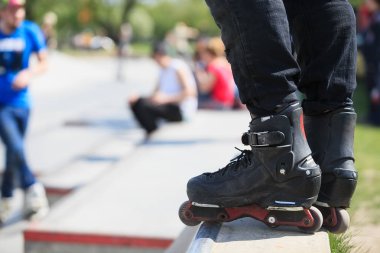 Açık skate Park beton rampa tepesinde duran agresif inline paten giymiş patenci ayakları. Silindir bıçakları için hile ve biler giyen aşırı spor atlet