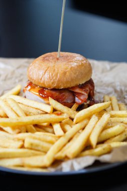 Jambon, ketçap sos ve patates kızartması tabak büyük şişman hamburger. Çok lezzetli ama sağlıksız beslenme menüsünde restoran. Burger plaka dilimlenmiş patates kızartması ile servis. Fast food Cafe menü