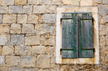 Antik Ev duvarında eski paslanmış pencere kepenkleri. Sarı taş tuğla bina. Geleneksel Hırvat mimarisi.