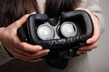 Mobil oyun uygulama için modern sanal gerçeklik gözlük tutan kadın. Mobil app kullanın, video oyun üstünde belgili tanımlık gitmek. Yakın çekim, eller içinde vr kulaklık odaklanmak. Trendy yeni augmented reality gaming aygıt