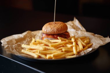 Fast food kafe menülerinde altın patates kızartması ile servis edilen domates ketçap soslu lezzetli hamburger. Restoran yemeği yakın. Kızarmış hamburger.