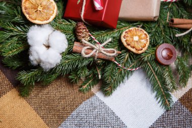 Rustik Noel dekorasyonu. Güzel el yapımı çam köknar ağacı çelenk, tarçın çubuğu, dyred turuncu meyve ve mum. Yeni yıl el ev dekorasyon kare kumaş üzerine hazırlanmış