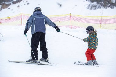Bukovel, Ukrayna-19 Mart, 2018: Ski Bukovel Winter Park içinde sürme sıcak kış spor giyim küçük çocukta. Koruyucu ekipman küçük çocuk freeskis kampında üst yardımıyla rides