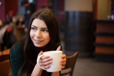 Genç güzel kız büyük bir kafede kahve fincan zevk