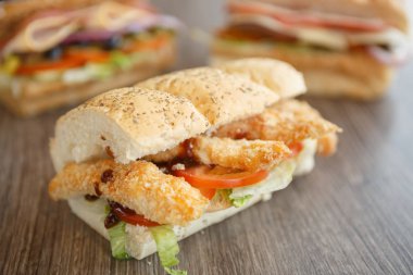 Fast food restoran menüsünde lezzetli sandviç. Taze aperatif kapatın. Kaşarlı tavuk şerit eti, dilimlenmiş domates sebze, salata yaprakları ve sos. Amerikan fastfood Cafe. Makro yakın çekim