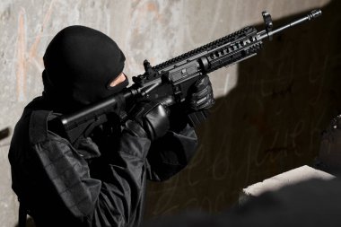 adam siyah kamuflaj ile bir otomatik Amerikan m-4 silah hedefleme