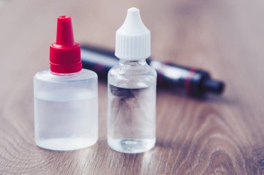 Vaping e-sıvı ile sigarayı vaping cihaz üzerinden. Tütün, probilen glicol ve gliserin temel olmadan sıvı dolum. Metin üzerinde şeffaf şişe yerleştirin.