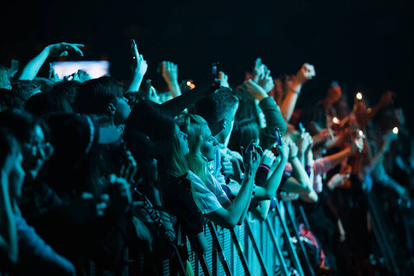 MOSCOW - 30 MARCH, 2017: Crowded dance floor at hip hop music concert.Big crowd of young people have fun,put hands up & film concert on mobile phones at security fence. Green lights
