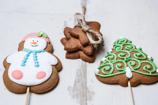 Three hand made Christmas and New Year holiday cookies.Sweet dessert food for celebration.Home made pastry products on white wooden background.Fir tree,snow man and stars