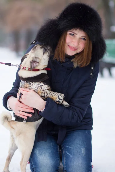 パグ面白い子犬公園に雪で遊んで赤い髪の十代の少女 — ストック写真