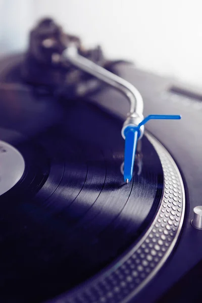 DJ turntable playing record with music.Analog audio equipment for disc jockey, night club or house party.Close up, focus on turntables needle over vinyl disc