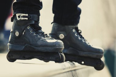 Agresif satır içi silindir blader ayak. Binici aşırı paten için siyah paten giymiş. Satır içi bıçaklar skatepark yaz aylarında açık egzersiz genç sporcunun ayak