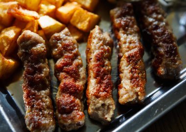 Geleneksel Sırp kavrulmuş et yemek ile kızarmış patates servis. Fast food restoran menüsünde egzotik ızgara biftek. Şişman füme çanak arka plan yakın çekim.