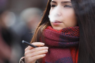 Uzun siyah saçlı elektronik sopa Sigara İçilmeyen ciddi genç kadınla. Modern ecig gadget nikotin sigarayı. Sigara içenler için Vaper aygıtı. E-cig vaping ejuice sıvı için