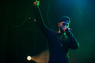 Moskova - 20 Ekim, 2016: Rap şarkıcı şarkı sahne gece kulübü. Hip hop müzik sanatçı şarkı mikrofon sahnede. Rapçi parlak konser aydınlatma.
