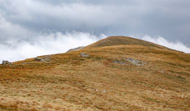 Karpat dağ tepe soğuk sonbahar günü dramatik bulutlu gökyüzü altında. Ağır sis Karpatlar tepelerde üzerinde haddeleme.