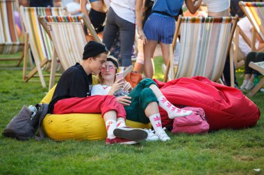 Kiev-11 Ağustos, 2018: Grup yaz festivalinde Kurazh rahatlatıcı şezlong üzerinde insan. Mutlu genç çift loung bölgesinde eğlence olay akıllı telefonlar ile soğutma
