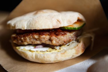 Huysuz topuz dekoratif kahverengi kağıt geleneksel Sırp Pljeskavica hamburger ızgara sığır eti, füme peynir dilimi ve sebze sos ile servis. Fast food restoran yemek yakın çekim