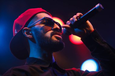 Moskova - 20 Ekim, 2016: Rap şarkıcı şarkı sahne gece kulübü. Hip hop müzik sanatçı şarkı mikrofon sahnede. Rapçi parlak konser aydınlatma.