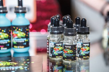 Kiev, Ukrayna-14 Nisan, 2018: yeni lezzetli vape suyu sigara elektronik vaping cihazlar ile için. Sigara içenler vape Expo Satılık. Plastik şişe kapları ile ejuice gliserin sıvı vaper mağaza