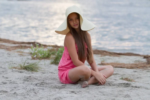 可爱的小女孩坐在海滩上的帽子 — 图库照片