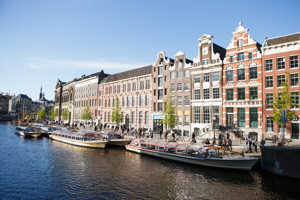 AMSTERDAM,NETHERLANDS-27 APRIL,2019: Flotaing houseboats in canal of river Amstel in historic center of Amsterdam city.Popular dutch boat houses drifting on water,moored on a pier