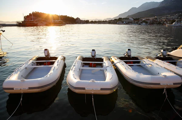 Rent motor boats for summer vacation trip.Rental inflatable water crafts with powerful engines parked in pier.Beautiful sunset view on haven with boats for rent.Enjoy holidays on seaside