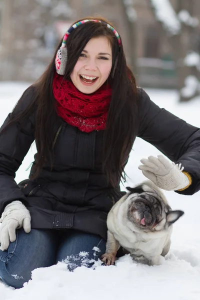 雪の中で面白いパグ子犬と遊ぶ若い Giel — ストック写真