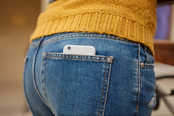 Big silver smart phone in back pocket of jeans.Camera lens in focus. Mobile photography is a trend, take photos,share with friends over internet with new smartphone