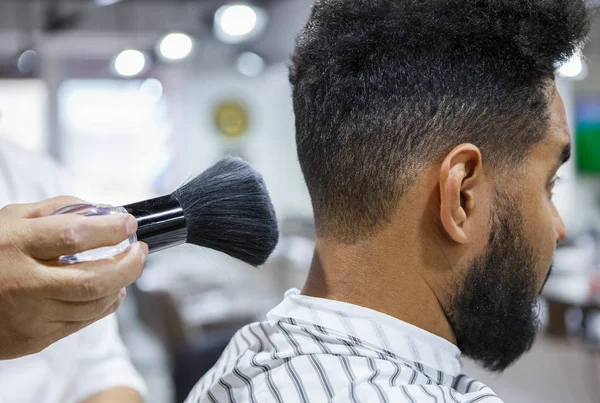 Barber uses shaving brush on clients neck to spread talcum powder for shaving neck with razor in barbershop .Male beauty treatment concept
