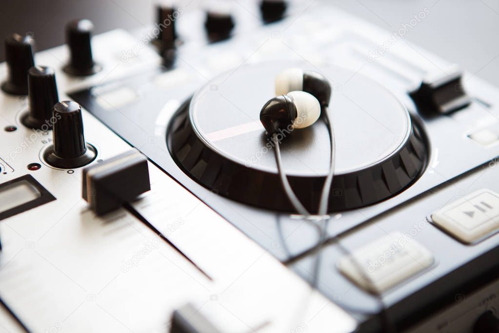 Headphones on DJ midi controller turntable. Close up on sound equipment. Knobs, fader, jog wheel