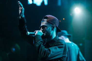 Moskova - 20 Ekim, 2016: Rap şarkıcı şarkı sahne gece kulübü. Hip hop müzik sanatçı şarkı mikrofon sahnede. Rapçi parlak konser aydınlatma.
