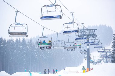 Bukovel, Ukrayna - 19 Mart, 2018: sandalye Asansör kayakçı ve Snowboard düşkünleri kış tatil için. Etkin turistler üzerinde snowboard binmek için Asansör ve kayaklar Bukovel Winter Park Karpat Dağları