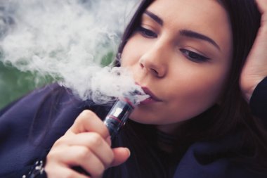Sigara nikotin çıkın, vaping e-suyu, e-sıvı başlar. Buharlaştırıcı aygıt, Sigara içenler için modern aracı kullanan genç ve güzel kadın. Güvenli ve lezzetli gliserin buharı