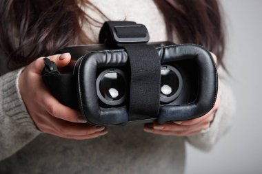 Kız modern sanal gerçeklik gözlük mobil oyun uygulama için basılı tutun. Mobil uygulamalar kullanmak, video oyunları her yerde oynamak. Yakın çekim, kadın elinde vr kulaklıktaki odaklan. Trendy yeni augmented reality gaming aygıt