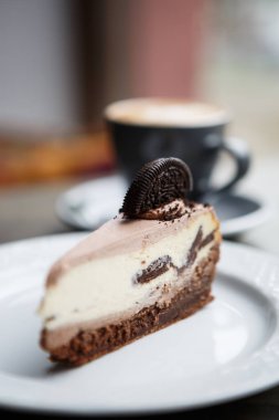 Lezzetli pasta çikolata bisküvi ve kakao çerez parça ile süslenmiş krem ile yemek. Lezzetli ekmek ürün kafede beyaz tabakta servis. Tablo pencerenin öğle yemeği için yakın