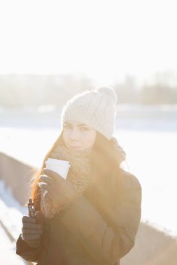 Kahve fincanı ve ecig ile genç ve güzel kız. Vaping aygıt bırakmak sigara, içki stres serbest bırakmak için kafeinsiz. Parlak güneşli kış günü. Atış, kopya alanı metin yukarıda çok kadın modeli için dikey